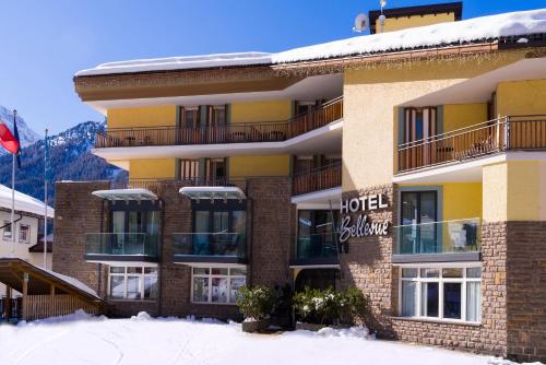 un bâtiment avec de la neige devant lui dans l'établissement Hotel Bellevue, à Canazei