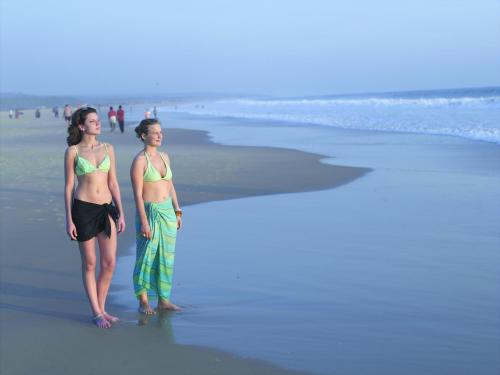 two people in bikinis standing on the beach at AyurSoma Ayurveda Royal Retreat in Kovalam
