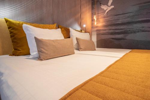 a large bed with white sheets and pillows at Grand Hotel Beatrix in Den Helder