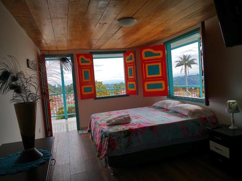 a bedroom with a bed in a room with windows at Casa Pachamama in Salento
