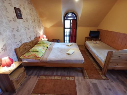 a bedroom with two beds and a table and a window at Hegyi Panzió in Szilvásvárad
