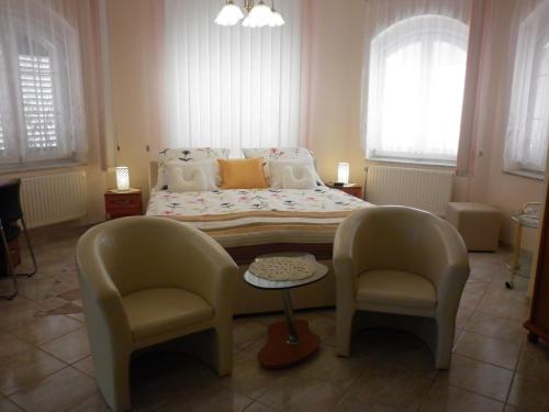 a bedroom with a bed with two chairs and a table at Manor Villa in Hévíz