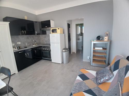 - une cuisine avec un réfrigérateur blanc et un canapé dans la chambre dans l'établissement le manege vue panoramique, à Cassis