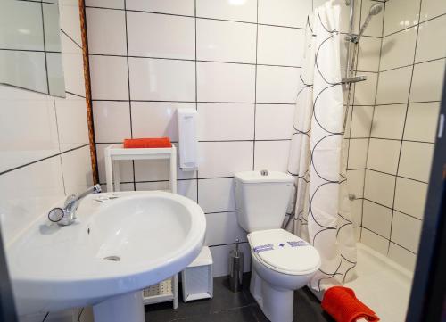 a white bathroom with a sink and a toilet at Itinere Rooms in Granada