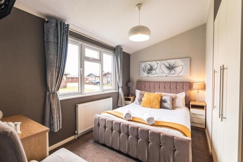 a bedroom with a large bed and a window at Kingfisher Lodge with Hot Tub in Malton