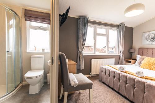 a bedroom with a bed and a toilet and windows at Kingfisher Lodge with Hot Tub in Malton