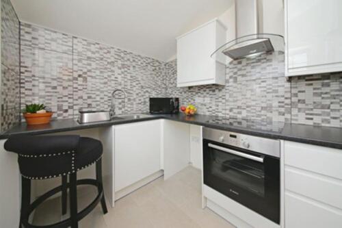 a kitchen with white cabinets and a black stove top oven at Imperial Guest House Ltd. in Hounslow