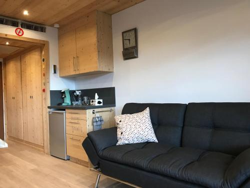 a living room with a couch and a kitchen at Ambrunes 9 - Grand studio rénové dans le centre de Châtel in Châtel