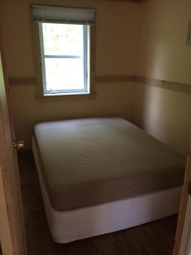 a bed in a room with a window at paradis sauvage geronimo in St-Etienne de Bolton