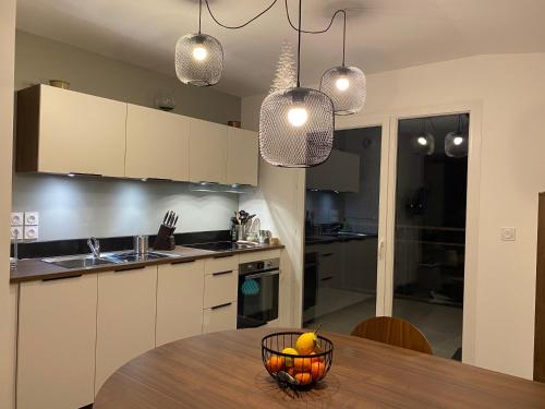 une cuisine avec une table avec un bol de fruits dessus dans l'établissement LES MYRTILLES Aix les Bains, à Aix-les-Bains