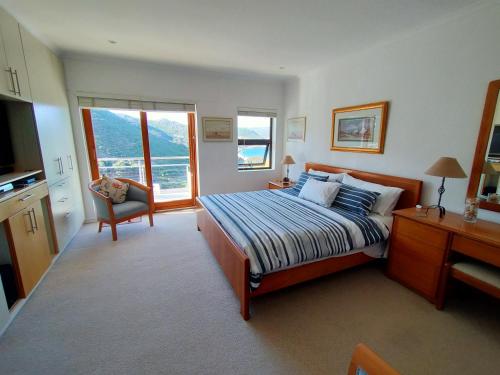 a bedroom with a bed and a desk and window at Admiral's Waterfall Self-Catering in Simonʼs Town