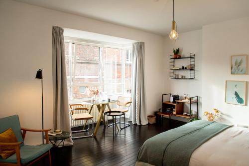 een slaapkamer met een bed en een tafel en stoelen bij huisalfons in Mechelen