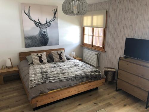 a bedroom with a bed and a deer painting on the wall at Le Cerf, magnifique studio avec jardin-terrasse et garage in Evolène