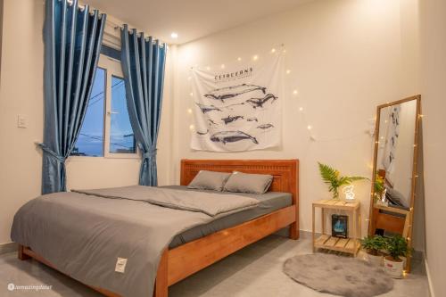 a bedroom with a bed with blue curtains and a window at Nhà của Sóc in Da Lat