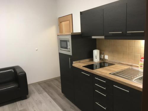 a kitchen with black cabinets and a sink and a microwave at Penzion Amálka in Třeboň