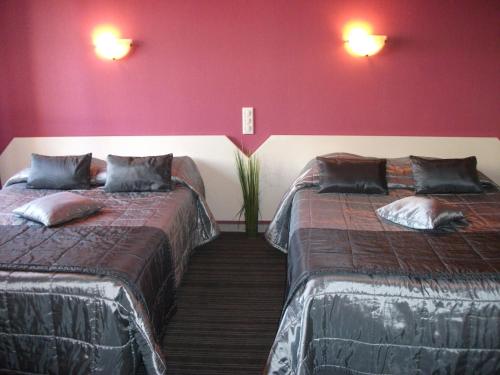 two beds in a room with red walls at Hôtel Le Michelet in Gap