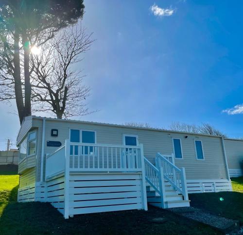 a mobile home with a porch and a tree at Newquay Bay Resort - SummerBreeze PV54 in Newquay Bay Resort