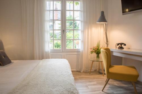 a bedroom with a bed and a chair and a window at Hôtel Le Plantagenet in Chinon