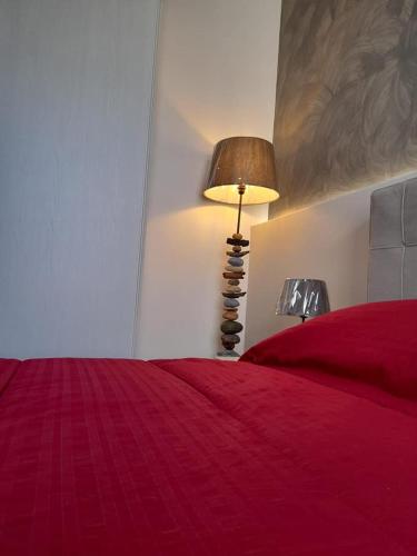 a bedroom with a red bed and a lamp at Dimora Palma in Alberobello