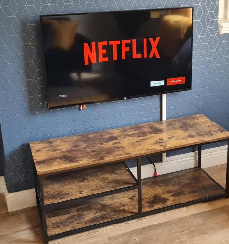 a tv sitting on top of a wooden table at Family friendly, Modern House just 1m from Bike Park Wales in Merthyr Tydfil