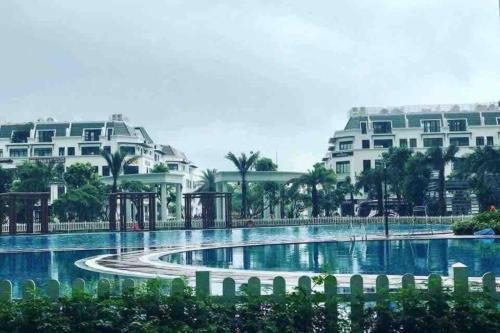 une piscine devant deux grands bâtiments blancs dans l'établissement 2 Bedrooms in luxury @Vinhomes Green Bay Ha Noi., à Hanoï