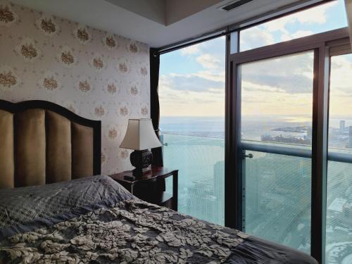 a bedroom with a bed and a large window at Two BD CN Tower and Lake Ontario View in Toronto