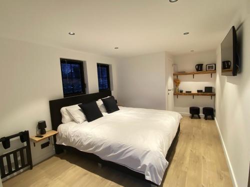 1 dormitorio con 1 cama blanca grande y 2 ventanas en Damse Paveljoentje comfort en uitzicht in Damme, en Damme
