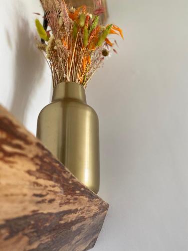a gold vase with flowers in it on a table at Damse Paveljoentje comfort en uitzicht in Damme in Damme