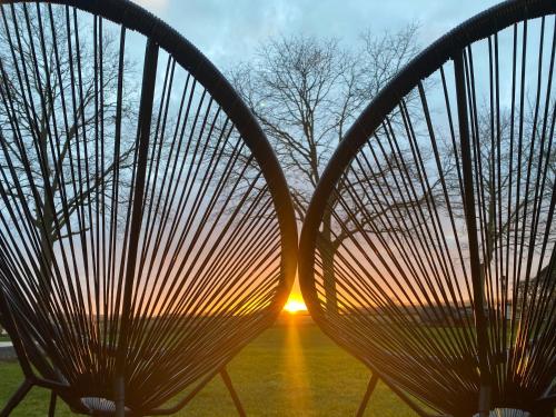 a couple of chairs with the sunset in the background at Damse Paveljoentje comfort en uitzicht in Damme in Damme