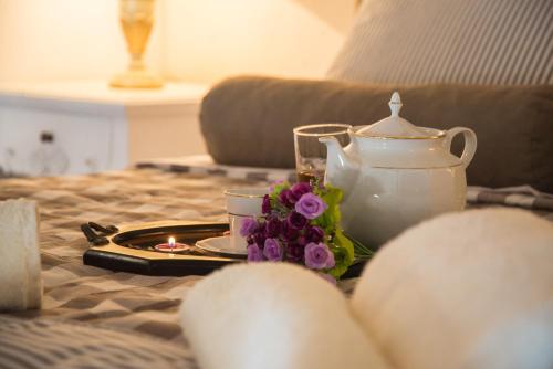 a tea set on a table with a tea pot and flowers at Porto Enetiko Suites in Rethymno Town