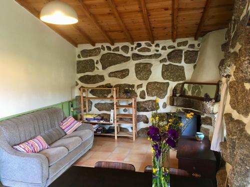 uma sala de estar com um sofá e uma parede de pedra em Quinta do Sobral de São Geraldo em São Geraldo