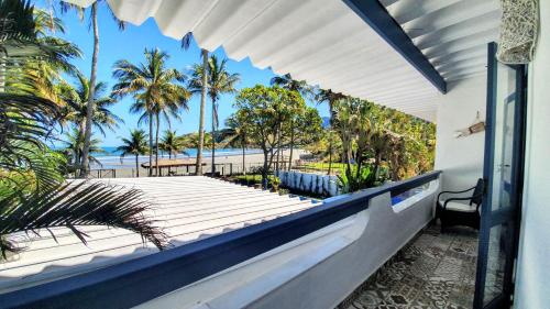 uma varanda com vista para a praia e palmeiras em Brisa do Mar Barê Praia Hotel - Praia de BAREQUEÇABA em São Sebastião