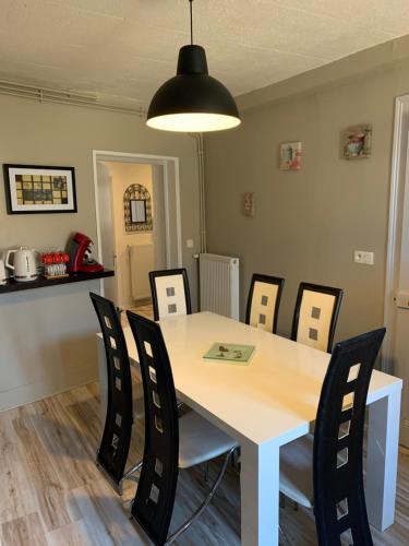 une salle à manger avec une table et des chaises blanches dans l'établissement Appartement de la nation 2, à La Tour-du-Pin