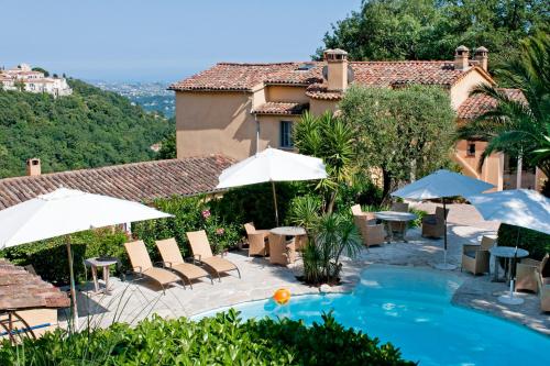 une piscine avec des chaises et des parasols ainsi qu'une maison dans l'établissement La Colline de Vence, à Vence