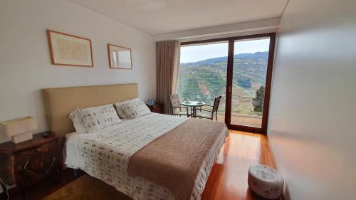 a bedroom with a bed and a large window at Imaginário D'El Rei - Guest House in Mesão Frio