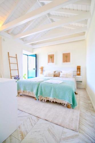 a white bedroom with a large bed with green sheets at FISH HOUSE 1 in Prainha de Cima