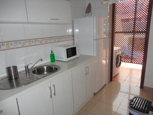 a kitchen with white cabinets and a sink and a microwave at Residencial Atlantico I in Costa Del Silencio