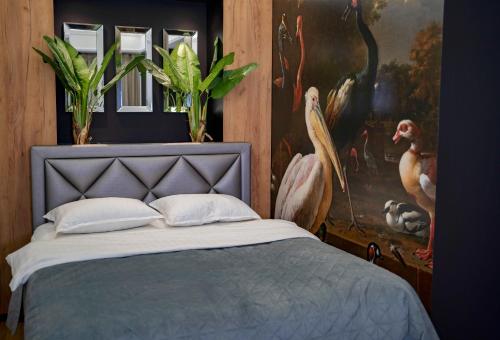 a bedroom with a bed with a painting of birds at The Main Square Apartments in Banja Luka