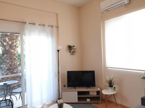 sala de estar con TV y ventana en Elegant Glyfada Apartment-private Garden-Near METRO, en Atenas