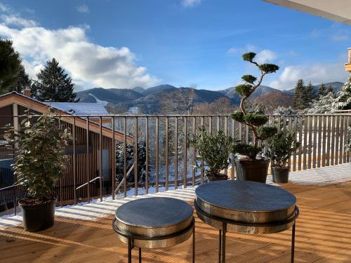 a balcony with two stools and a table on a deck at Tegernsee - Seeblick, Terrasse, Berge in Tegernsee