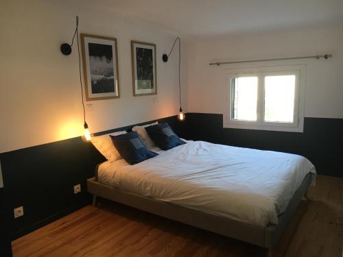 a bedroom with a bed with two lights on it at Cilaos - maisonnette médocaine avec terrasse attenante face au gîte in Saint-Laurent-de-Médoc