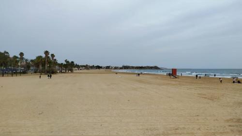 een strand met mensen die over het zand en de oceaan lopen bij Cambrils Bahía in Cambrils