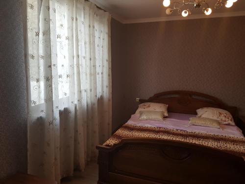 a bedroom with a bed and a window with curtains at Домик из двух комнат + кухня столовая с удобствами, со своим двориком под ключ in Sukhum