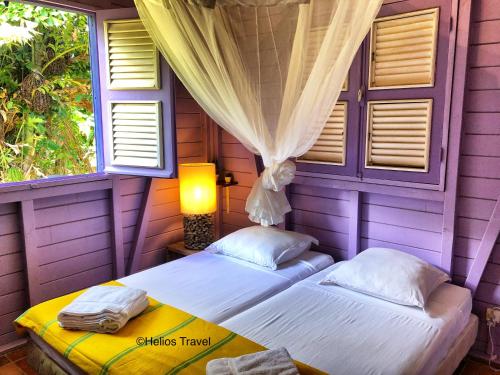 two beds in a purple room with two windows at Villa Deshaies in Deshaies