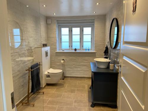W łazience znajduje się toaleta, umywalka i lustro. w obiekcie Lindegaardens Bed and Breakfast w mieście Viby