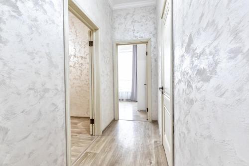 een hal met witte muren en een spiegel bij Апартаменты Променад экспо 269 in Astana