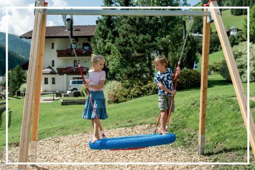 two young children playing on a swing set at Tyrol Mountain Aparts - Urlaubsresort Hafele in Sankt Jakob in Defereggen