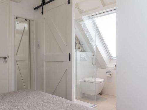 een witte badkamer met een toilet en een raam bij Vakantiewoningen Prelude & Etude in Wieringerwaard