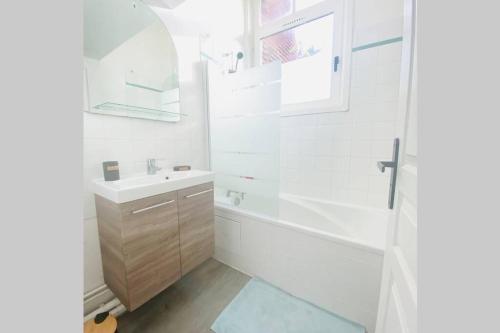 uma casa de banho com uma banheira, um lavatório e um espelho. em Proche Golf Appartement 4pers avec parking piscine tennis em Neufchâtel-Hardelot