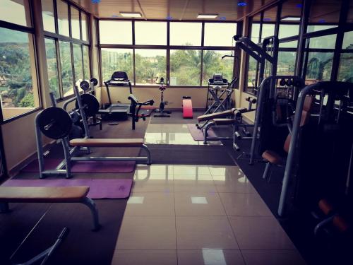 a gym with treadmills and chairs in a room with windows at La Couronne Suites in Bangui